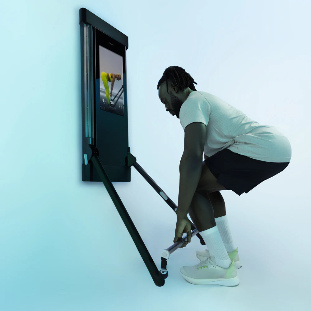 Man performing a workout with a wall-mounted Tonal resistance trainer.