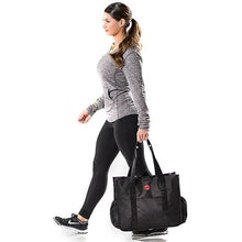 Woman in gray athletic wear walking with a black tote bag.