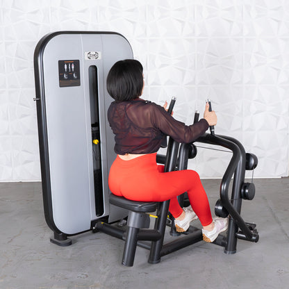 Woman using a seated row machine in bright red leggings for strength training.