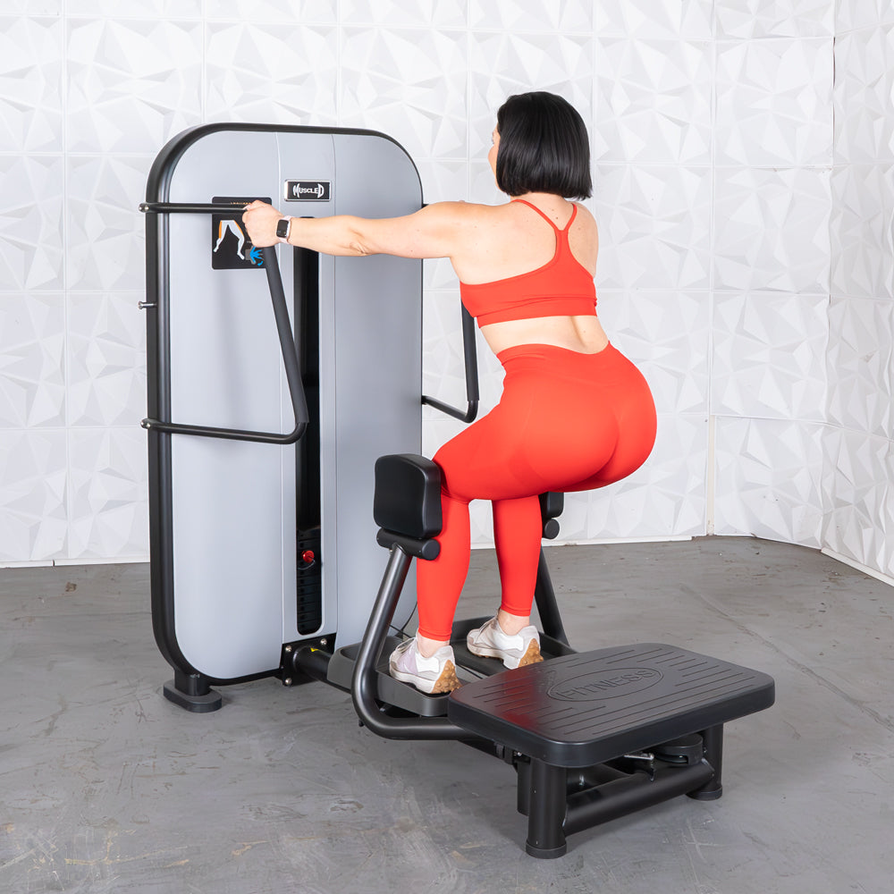 Woman in red workout outfit using a standing hip abductor machine.