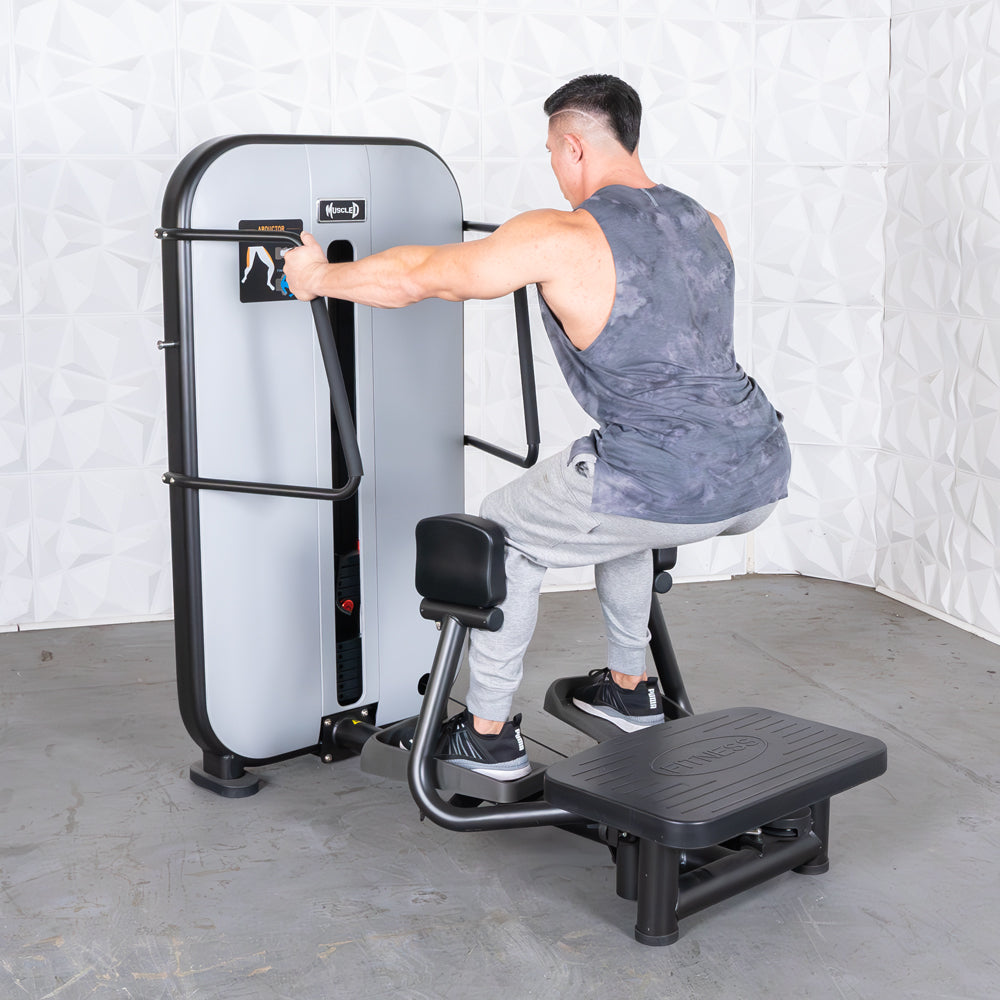 Man uses standing hip abductor machine at the gym.