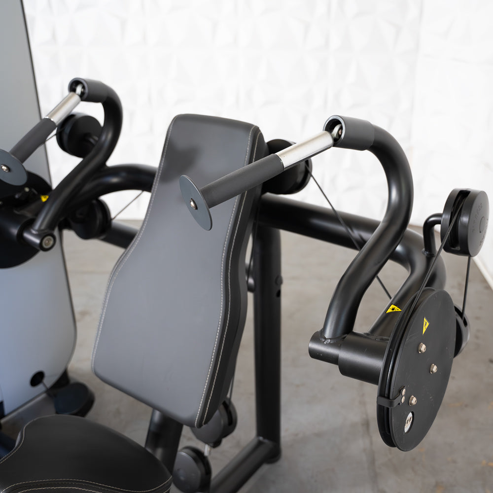 Triceps extension station on fitness machine with padded arm pad.