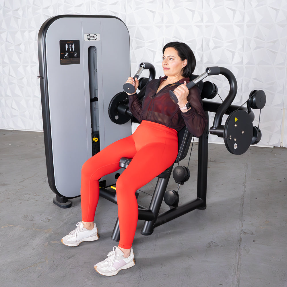 Woman using a triceps extension machine at the gym, wearing red leggings.