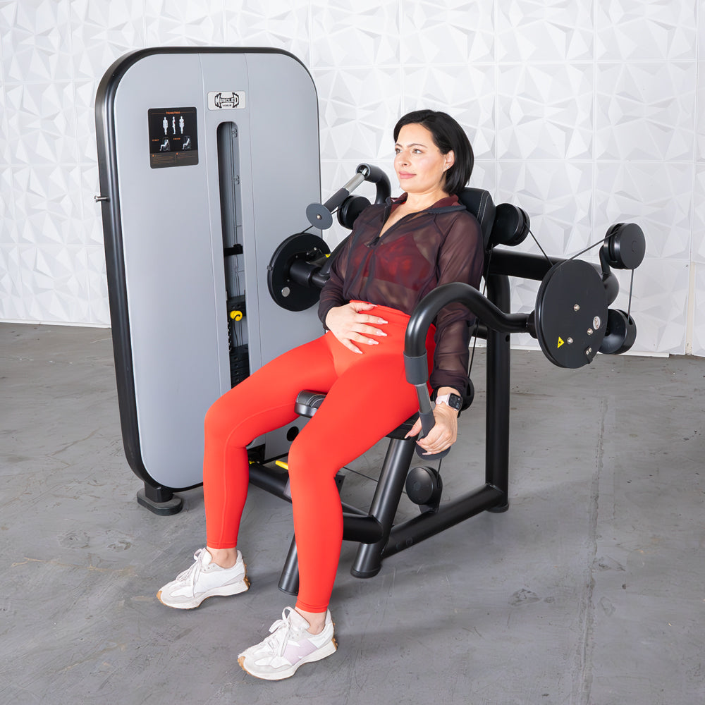 Woman in red leggings uses a triceps extension machine in a gym.
