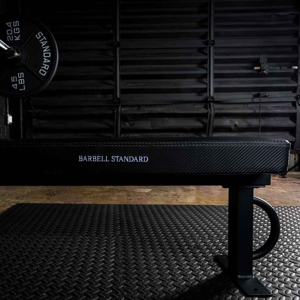 Barbell Standard bench in a gym with a weight plate on the left.