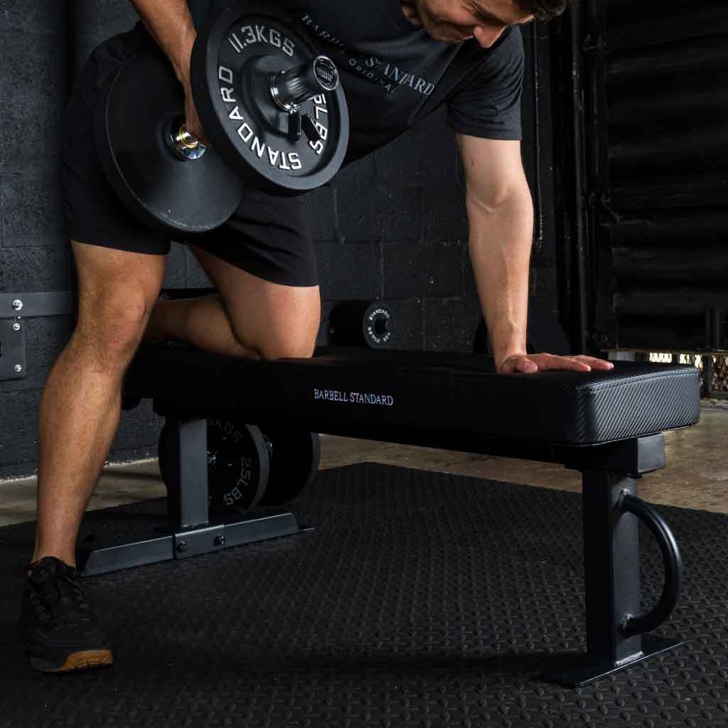 Athlete performing dumbbell rows on a flat bench.