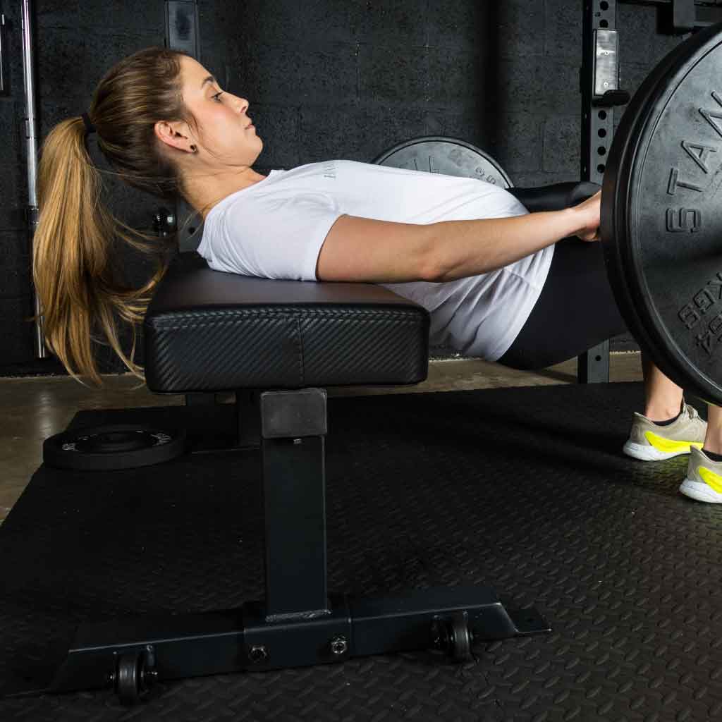 Woman performing hip thrust on a gym bench with a barbell.