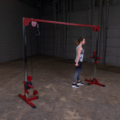 A woman performing a workout using a cable machine in a spacious gym environment, with a red and silver frame and adjustable pulleys.