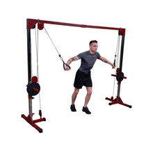 A young man with tattoos performing an exercise using a cable machine in a gym setting, showcasing strength training.