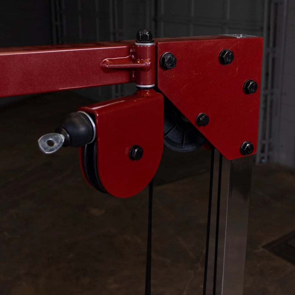 Close-up of a red pulley system with a metal frame, showcasing the connection points and bolts, set against a dark background.