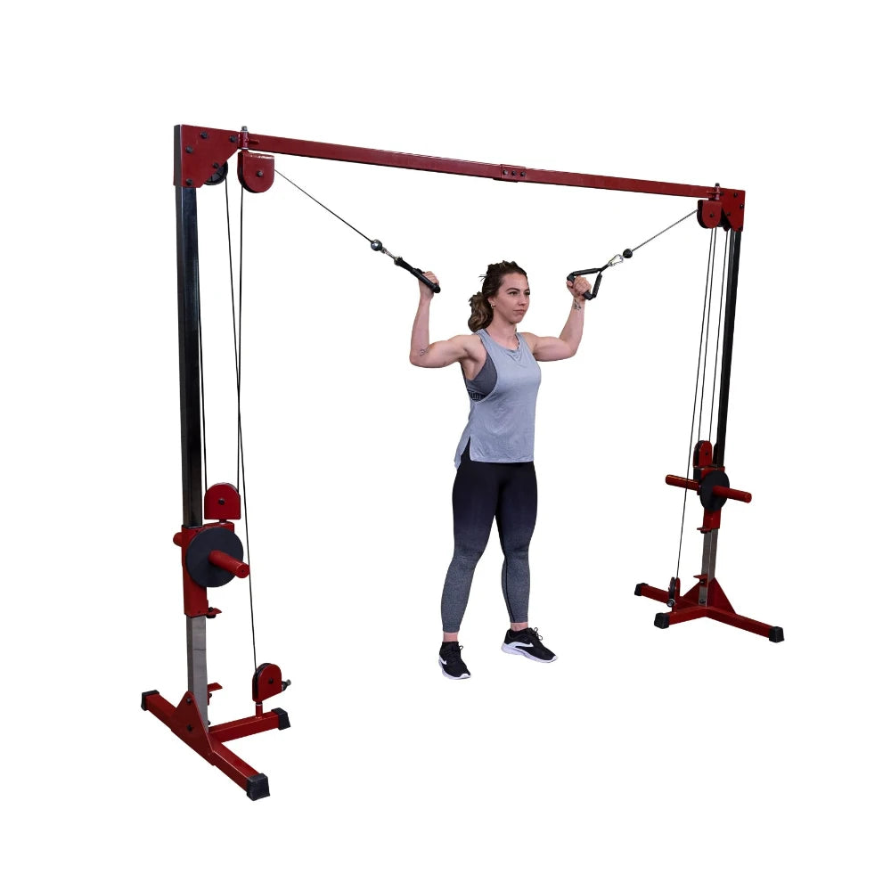 A woman performing an exercise using a cable machine, holding the handles with both hands, while wearing a gray tank top and black leggings.