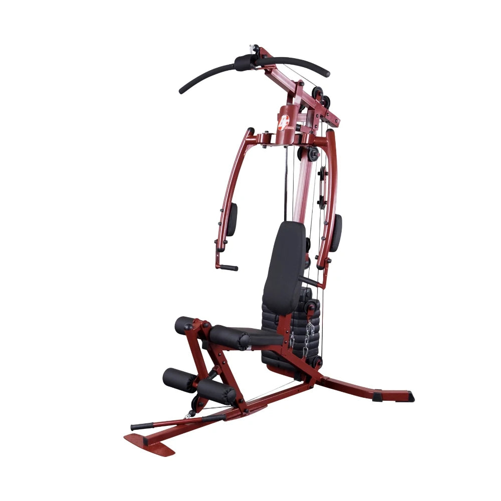 A red and black multi-gym exercise machine designed for strength training, featuring a padded seat, adjustable pulleys, and various attachments for different workouts.