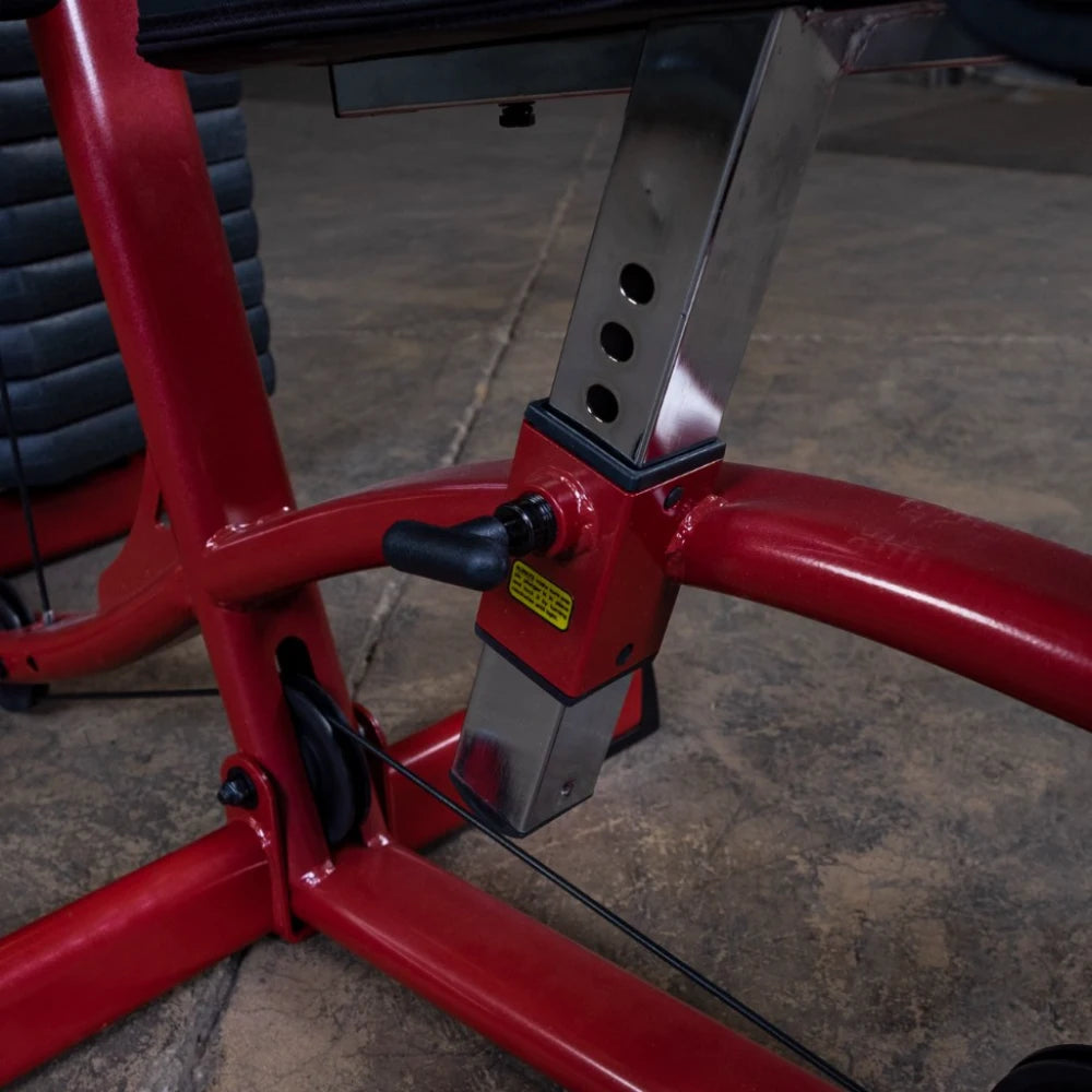Close-up of a red fitness equipment adjustment mechanism, featuring a metal lever and adjustable height settings, with a textured surface and visible cable.