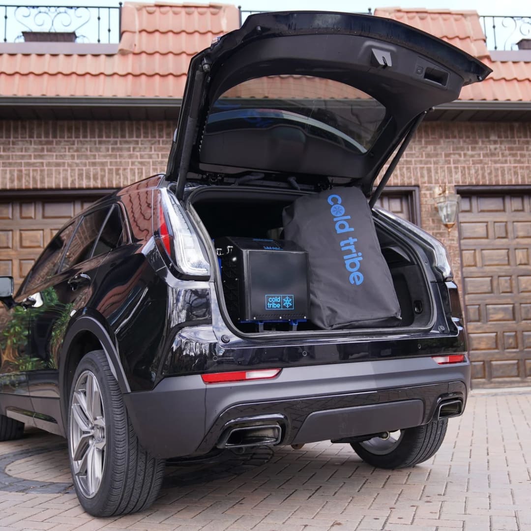 The trunk of a black SUV displaying a Coldture Classic cooler and a Chiller Pro bag from Cold Tribe.