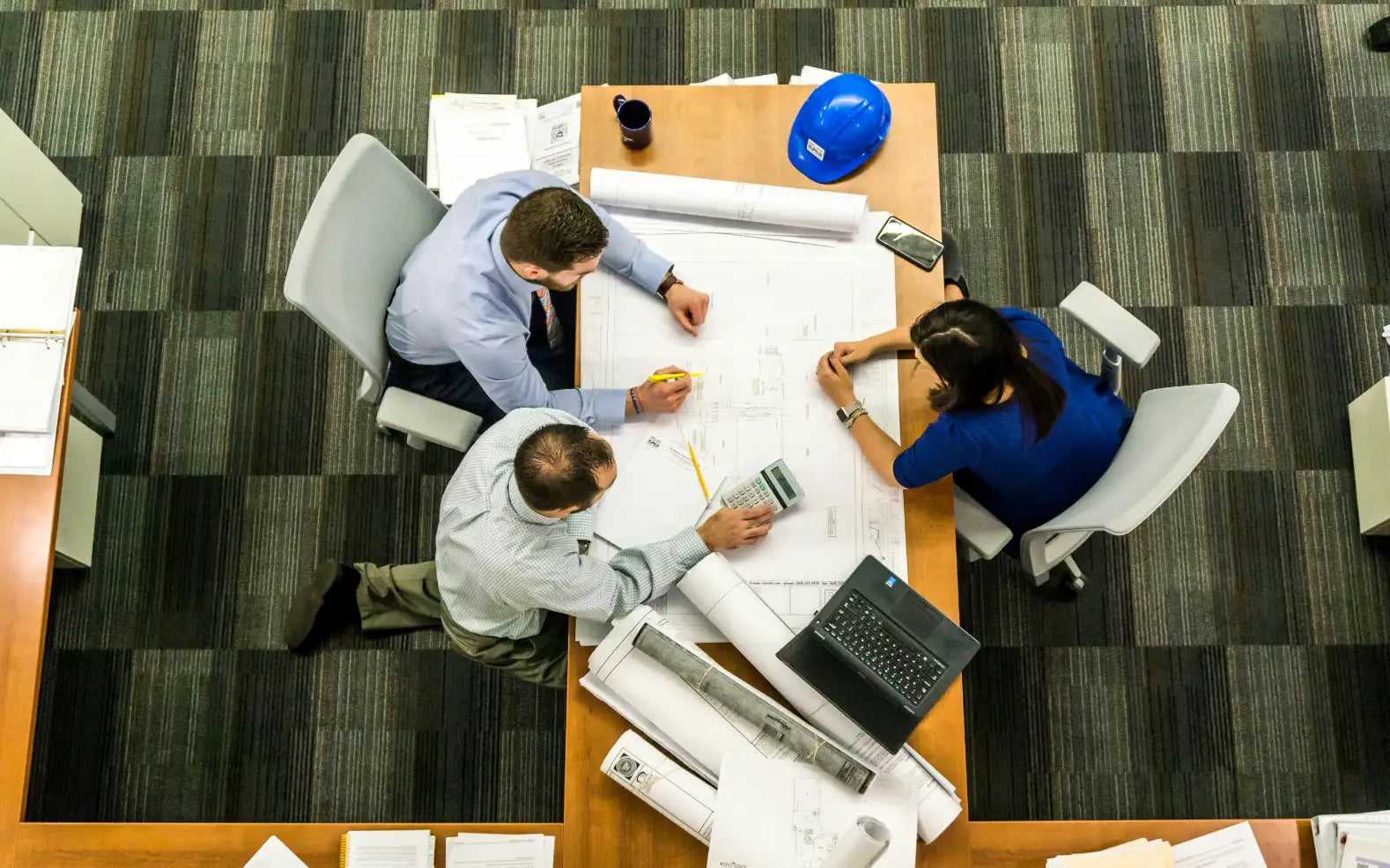 Overhead view of professionals reviewing architectural blueprints at a table.