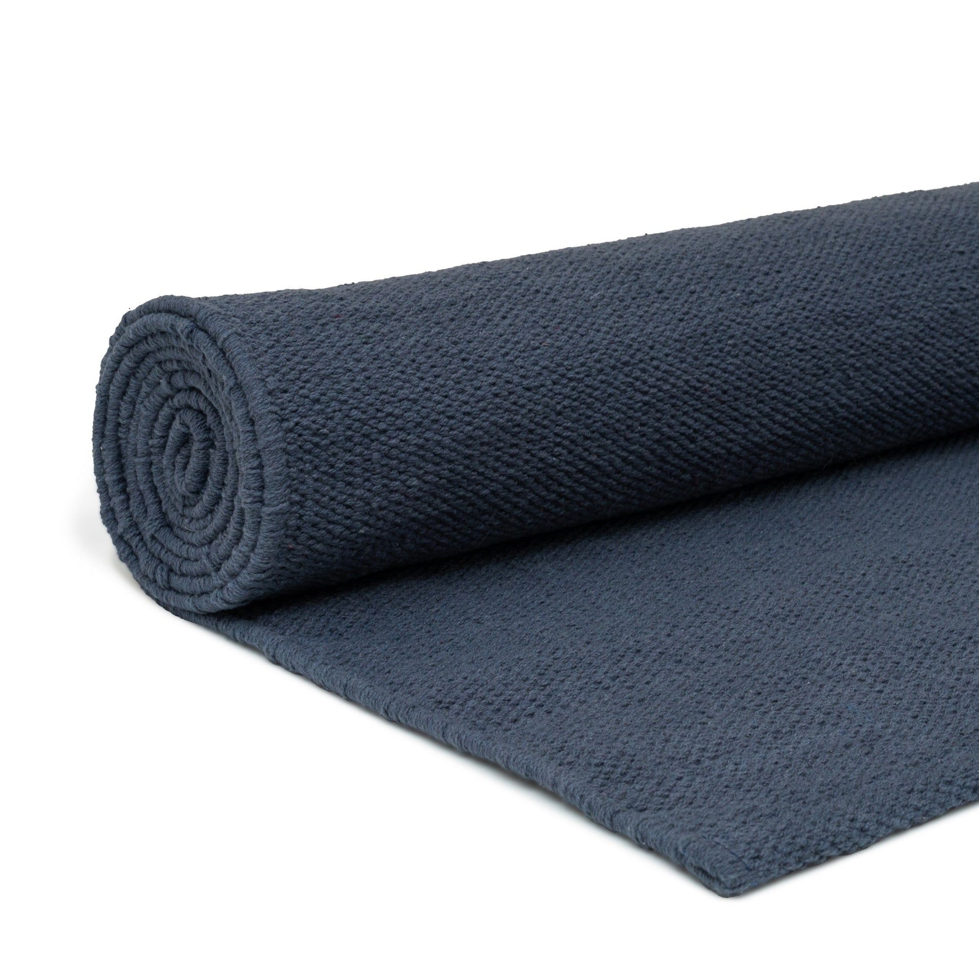 Rolled navy blue cotton yoga mat on white background.