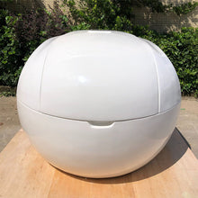 A white spherical pod, the Dreampod Home Float Plus, displayed outdoors with greenery in the background.