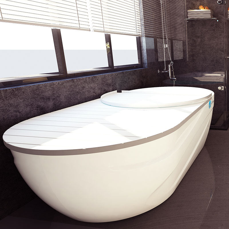 Dreampod Home Float Pro, a modern white floatation pod in a stylish bathroom setting with large windows and a sleek design.