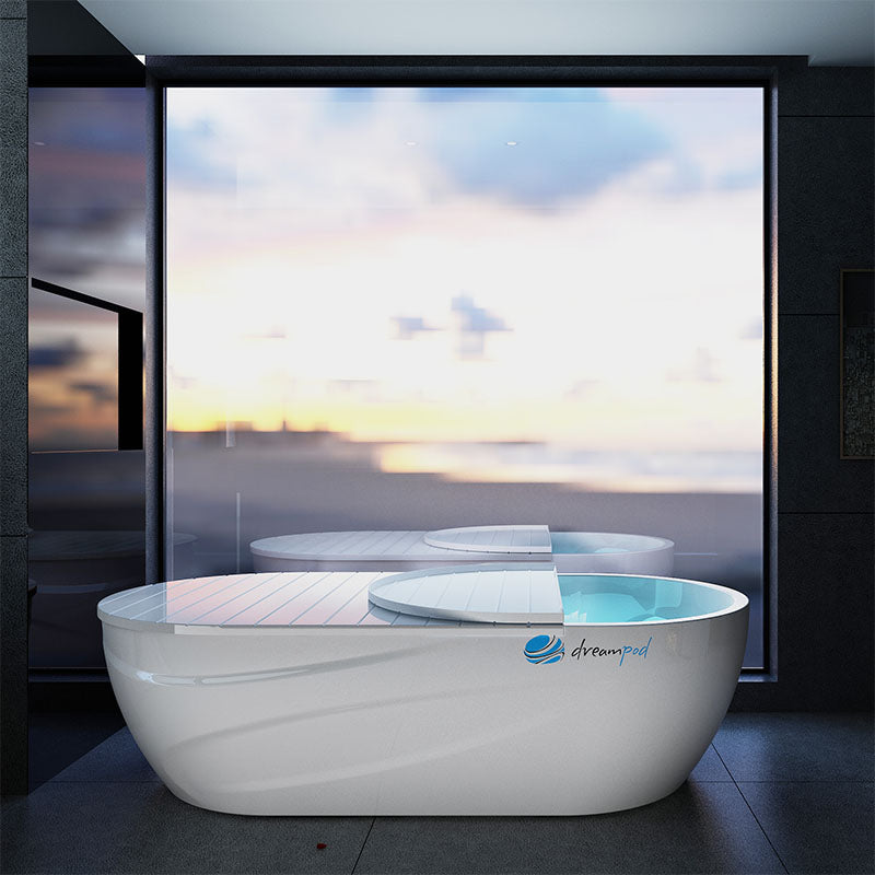 Dreampod Home Float Pro, a sleek white floatation pod with a minimalist design, situated in a modern room with large windows showcasing a serene outdoor view.
