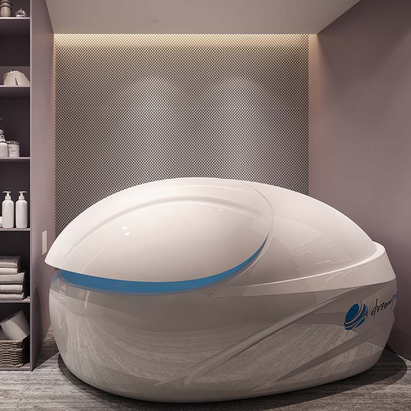 Dreampod V-Max Float Pod displayed in a modern spa setting with shelves containing spa products in the background.