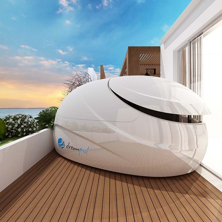 Dreampod V2 Float Pod situated on a wooden deck with a scenic view of the ocean and a cloudy sky in the background.