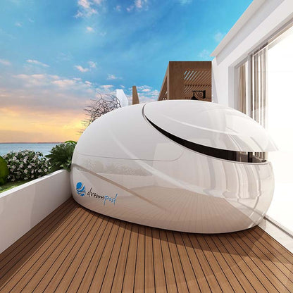 Dreampod V2 Float Pod situated on a wooden deck with a scenic view of the ocean and a cloudy sky in the background.