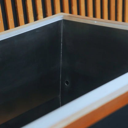 Close-up view of a modern, angular black metal sink with a silver edge, set against a backdrop of wooden vertical slats.