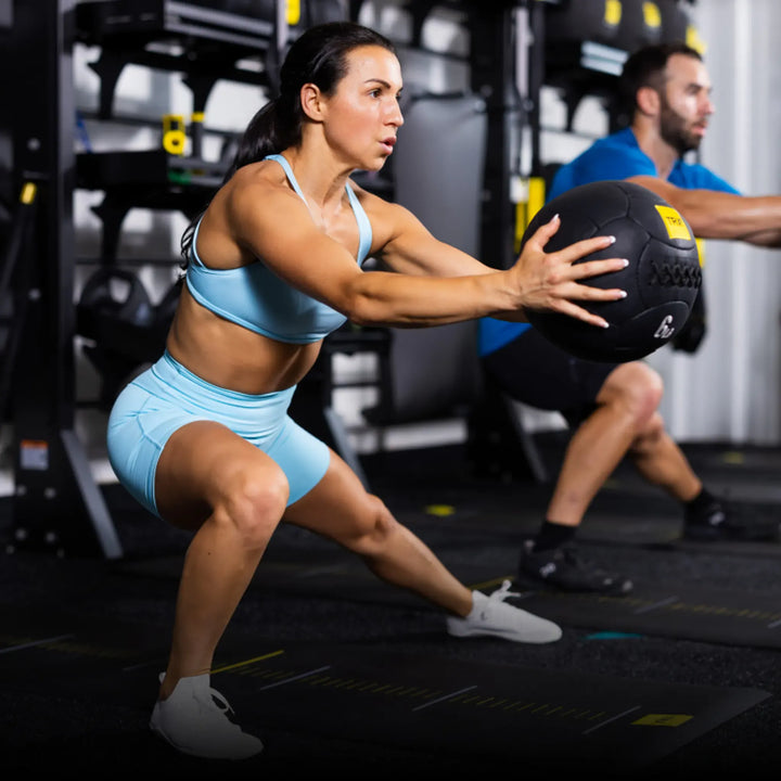 Woman exercising with a TRX medicine ball in fitness studio setting