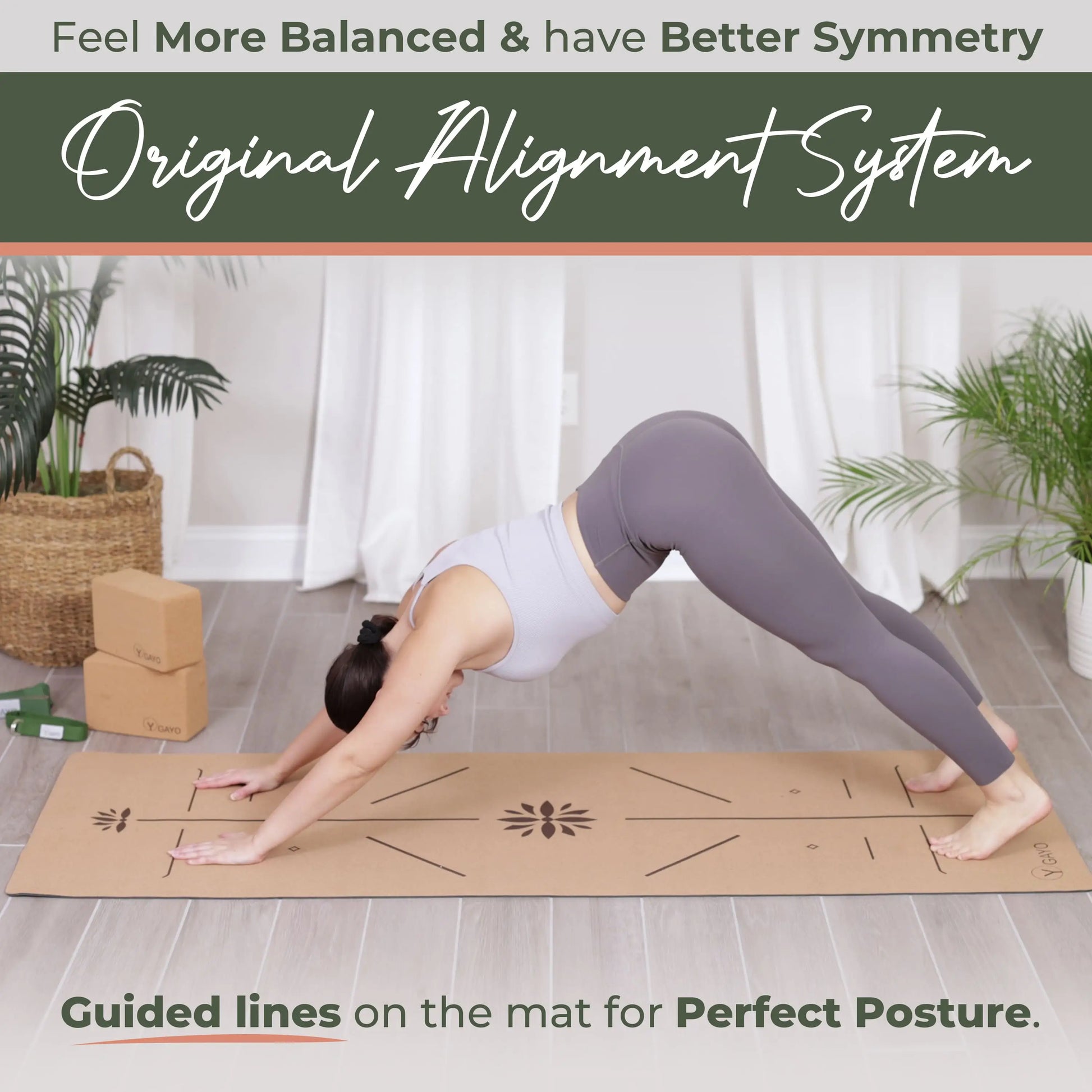 Woman in downward dog pose on a natural cork yoga mat with alignment guide lines printed across the surface, set in a bright room with potted plants and wooden props.