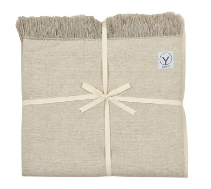 Cream-colored yoga blanket with textured hemp and organic cotton weave, fringed edges, tied with cream ribbon, and Gayo brand label visible.