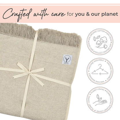 Cream-colored hemp and organic cotton yoga blanket with fringed edges, tied with a cream ribbon bow, displaying GAYO brand label and three circular icons indicating organic cotton, machine washable, and planet-loving materials.