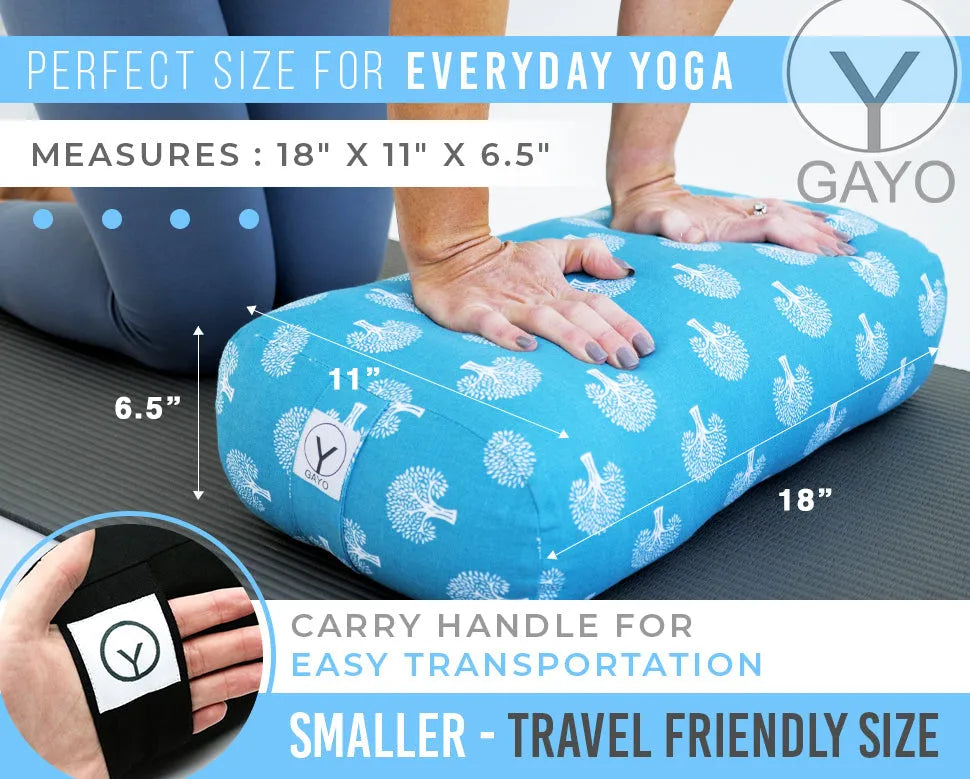 Bright turquoise yoga bolster with white leaf pattern, measuring 18" x 11" x 6.5", displayed on a yoga mat with a person's hands resting on top. Black carry handle with GAYO logo visible on the cushion.