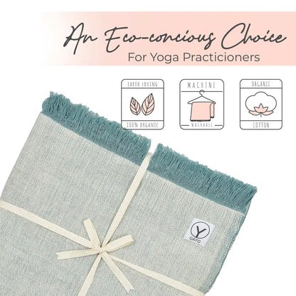 Two organic cotton yoga blankets with teal fringe edges and cream binding, displayed flat on a pink background. Product features icons highlight earth-loving 100% organic material, machine washable care, and organic cotton composition.