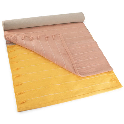 Rolled yoga mat with layered cotton fabric in beige, pink, and yellow colors, featuring a textured quilted surface and carrying handles.