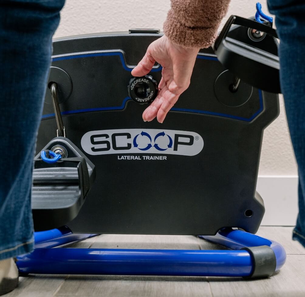 Person using a Scoop Lateral Trainer exercise machine with a hand on the handle.
