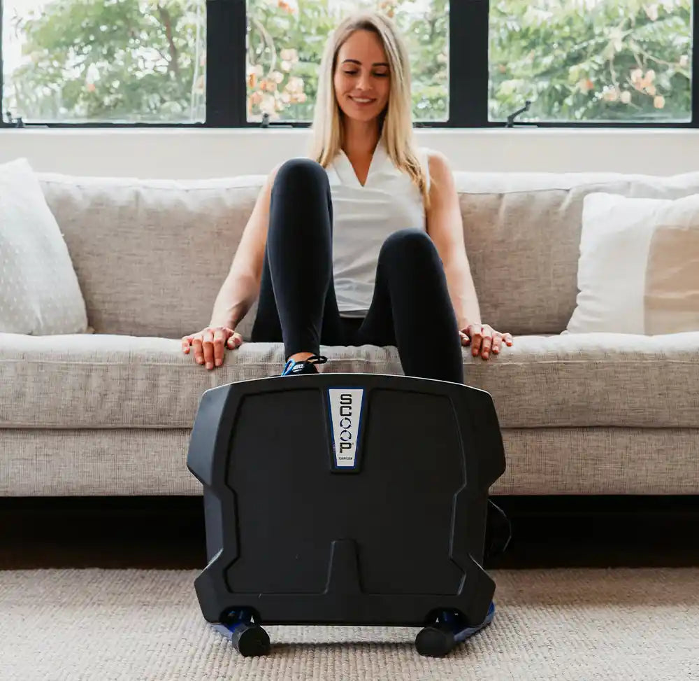 Woman using Helix Scoop Lateral Elliptical on the floor in a living room.
