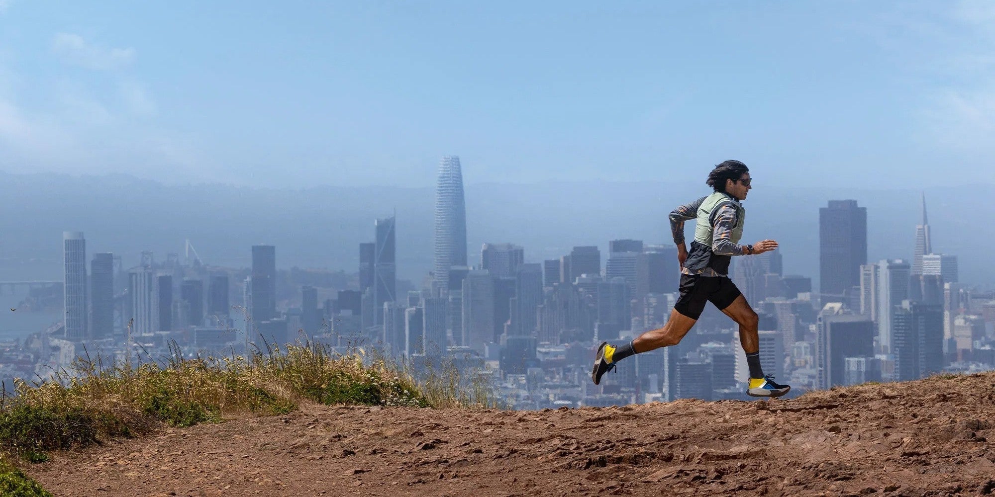 Person running on a trail with a city skyline in the background