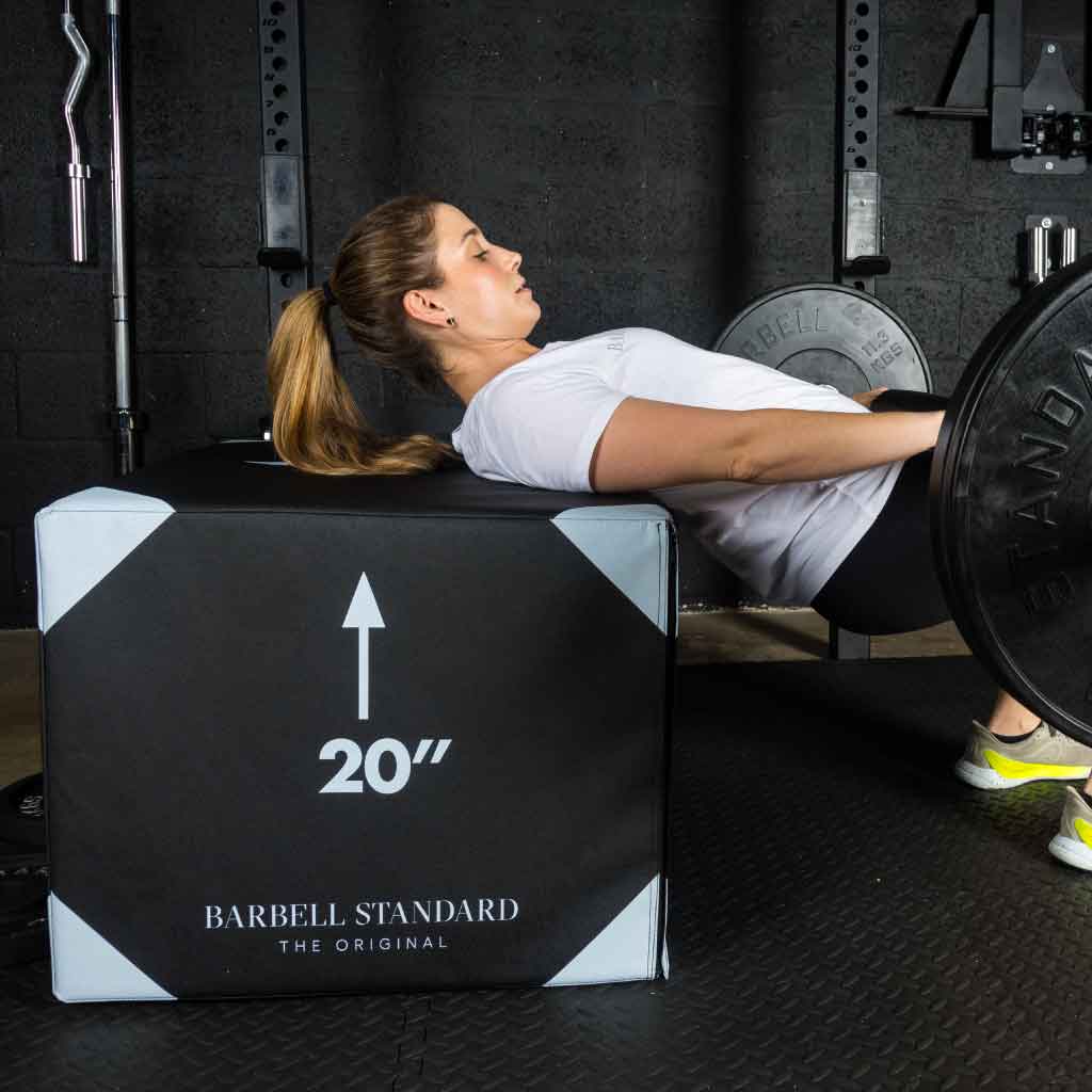 Woman performing a hip thrust on a 20-inch jump box in the gym.