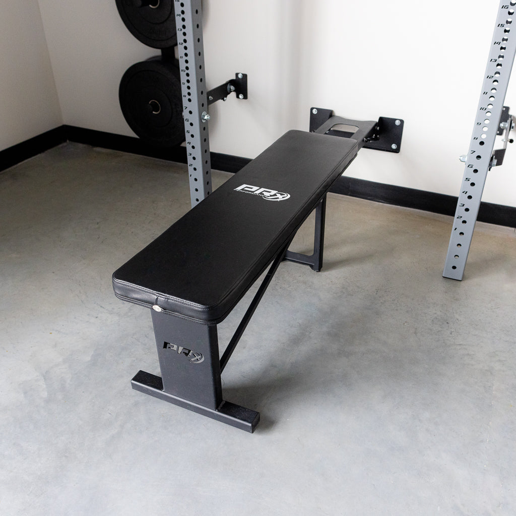 PRx folding flat weight bench in a gym with a squat rack.