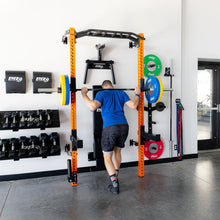 Person squatting with barbell on orange ProX squat rack in gym.