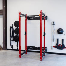 Red power rack in a home gym with weights and equipment.
