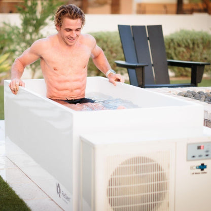 Man enjoying a cold plunge in a sleek white ice bath, promoting recovery and wellness.