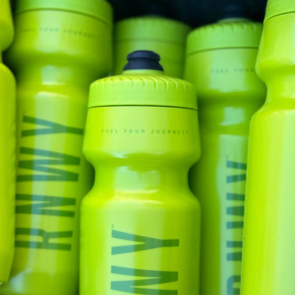Neon yellow sports water bottles with textured grip and dark blue flip-top caps, featuring teal graphic design and "Fuel your journey" text on the center bottle.
