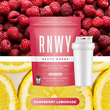Pink RNWY Salty Carbs pouch with white shaker bottle, displayed against fresh raspberries and lemon slices. Raspberry lemonade flavor endurance fuel with 30g carbohydrates and 700mg sodium per serving.