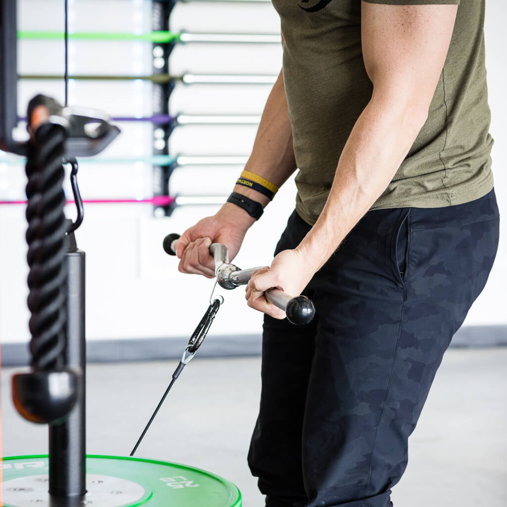Person gripping a cable curl bar attachment during a strength workout.