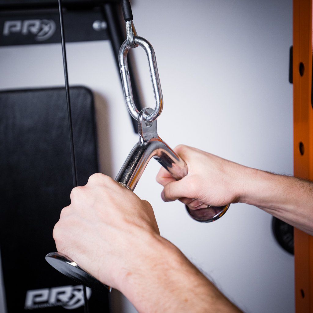Hands gripping a chrome V-bar handle attached to a cable pulley machine.