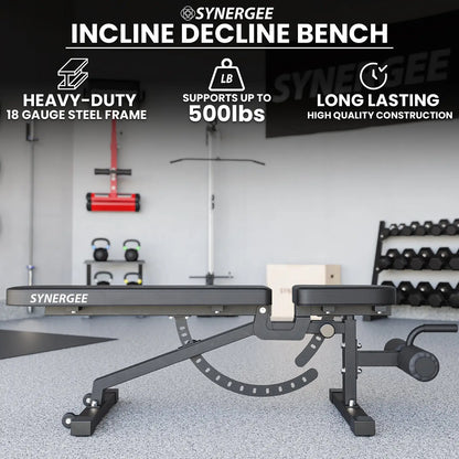 Synergee adjustable incline decline bench with black padded seat and backrest, angle adjustment mechanism visible underneath, positioned in a gym setting with kettlebells and dumbbells in the background.