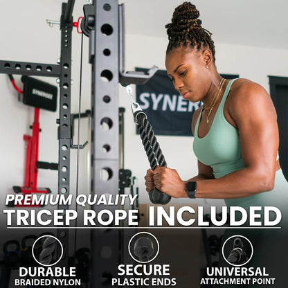 Woman performing a tricep rope exercise on a cable pulley machine with black and gray frame, holding the textured black braided rope attachment.
