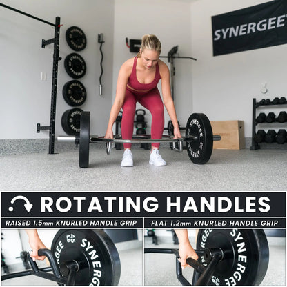 Woman performing a deadlift with a black hex trap bar featuring rotating handles in a gym setting with weight plates and equipment visible in background.