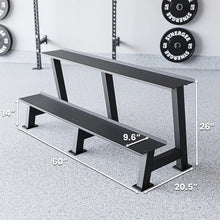 Two-tier black weight bench with metal legs positioned in a gym setting with a power rack and loaded plates visible in background. Dimensions labeled: 60" length, 26" height, 20.5" depth, and 9.6" seat width.
